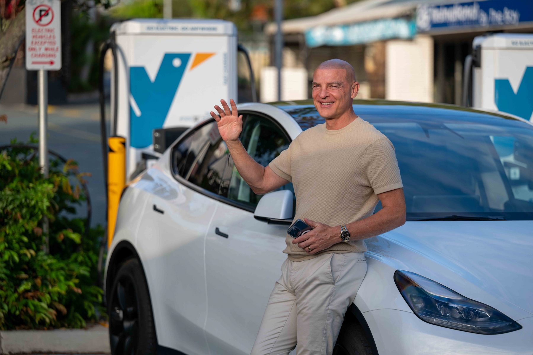 V2_Man leaning on Tesla car at Evie charger V2_Man leaning on Tesla car at Evie charger